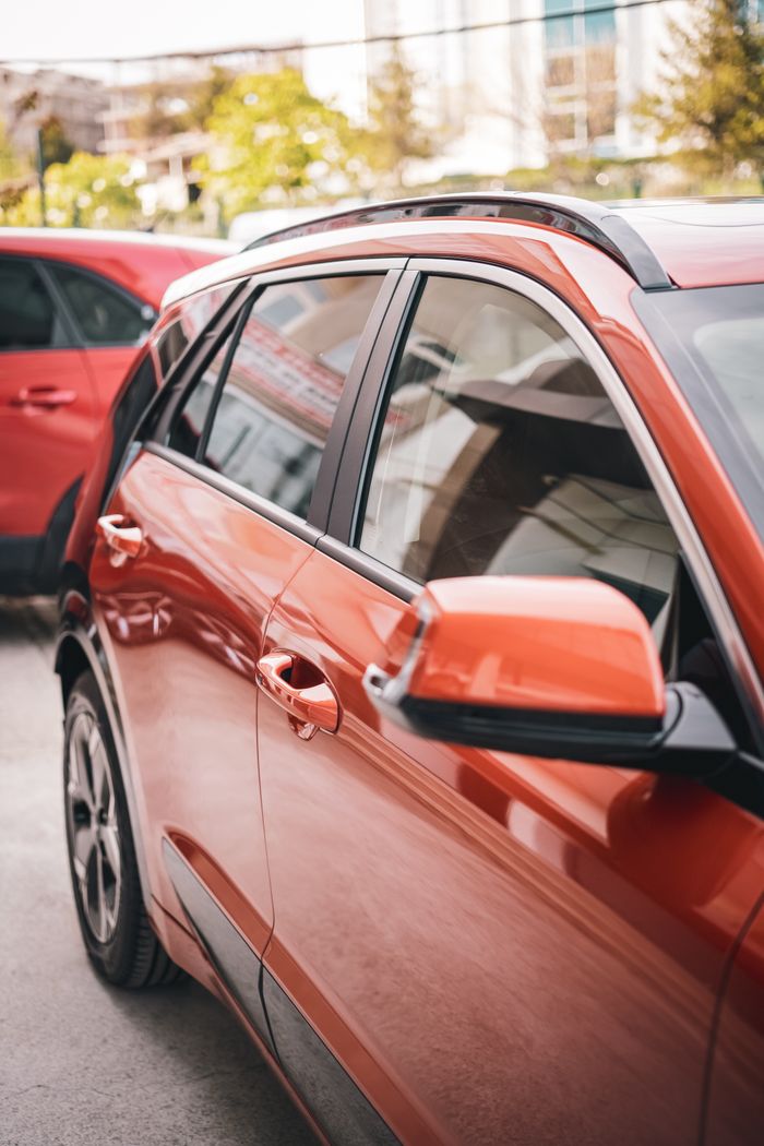 Close-up of a red crossover vehicle parked in a modern urban environment.