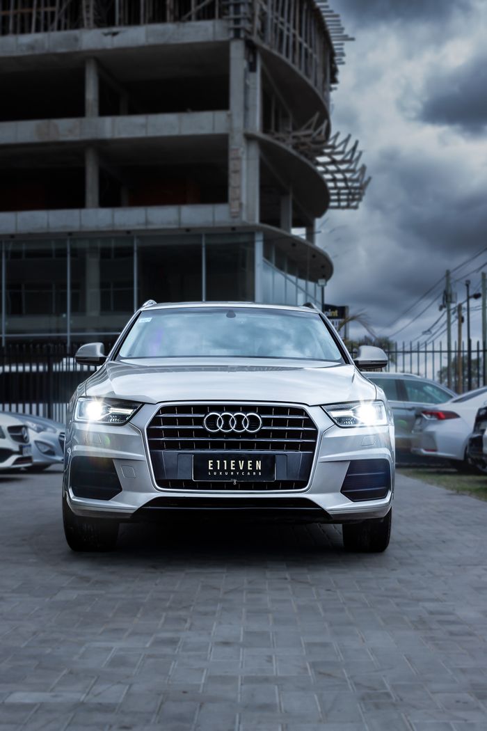 Front view of a modern Audi car parked in an urban setting with a dramatic sky.