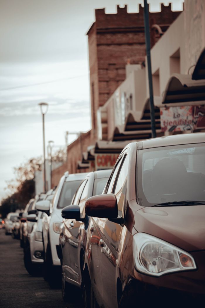 City street featuring parked cars with urban buildings in the background, showcasing traffic and city life.